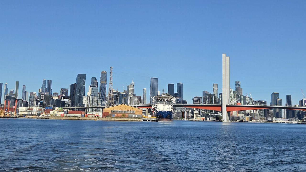 The Melbourne skyline seen across the water from Port Melbourne, with the Bolte Bridge and the working docks in front of it