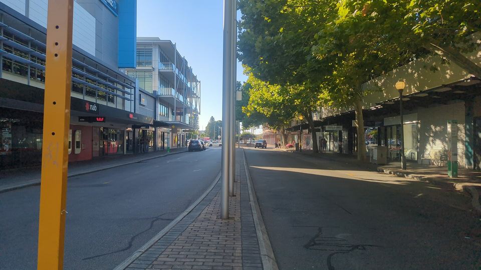 Queen Street in Fremantle on a sunny morning, plane trees over the footpath, shopfronts under their awnings and the road almost empty