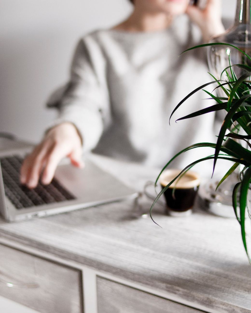 A recruiter on a phone call reaching for their laptop at a desk
